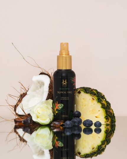Hydra Tropical Vibes pet cologne bottle with coconut, pineapple, white rose and blueberries on a reflective surface